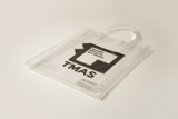 Angled TMAS Logo clear tote resting on ground