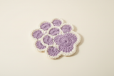 Purple and white crochet pawprint coaster - angled view